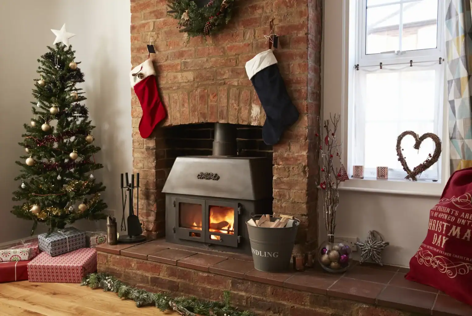 Holiday cottage living room with a lit log burner, Christmas tree and stockings