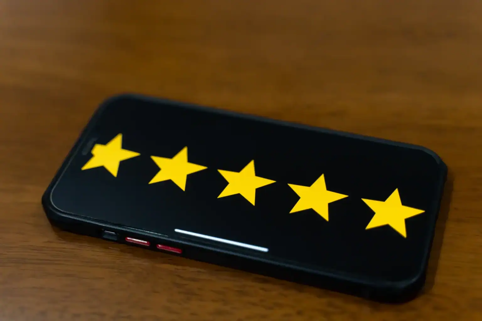 Smartphone on a wooden table showing a five-star rating – fake reviews are now illegal in the UK