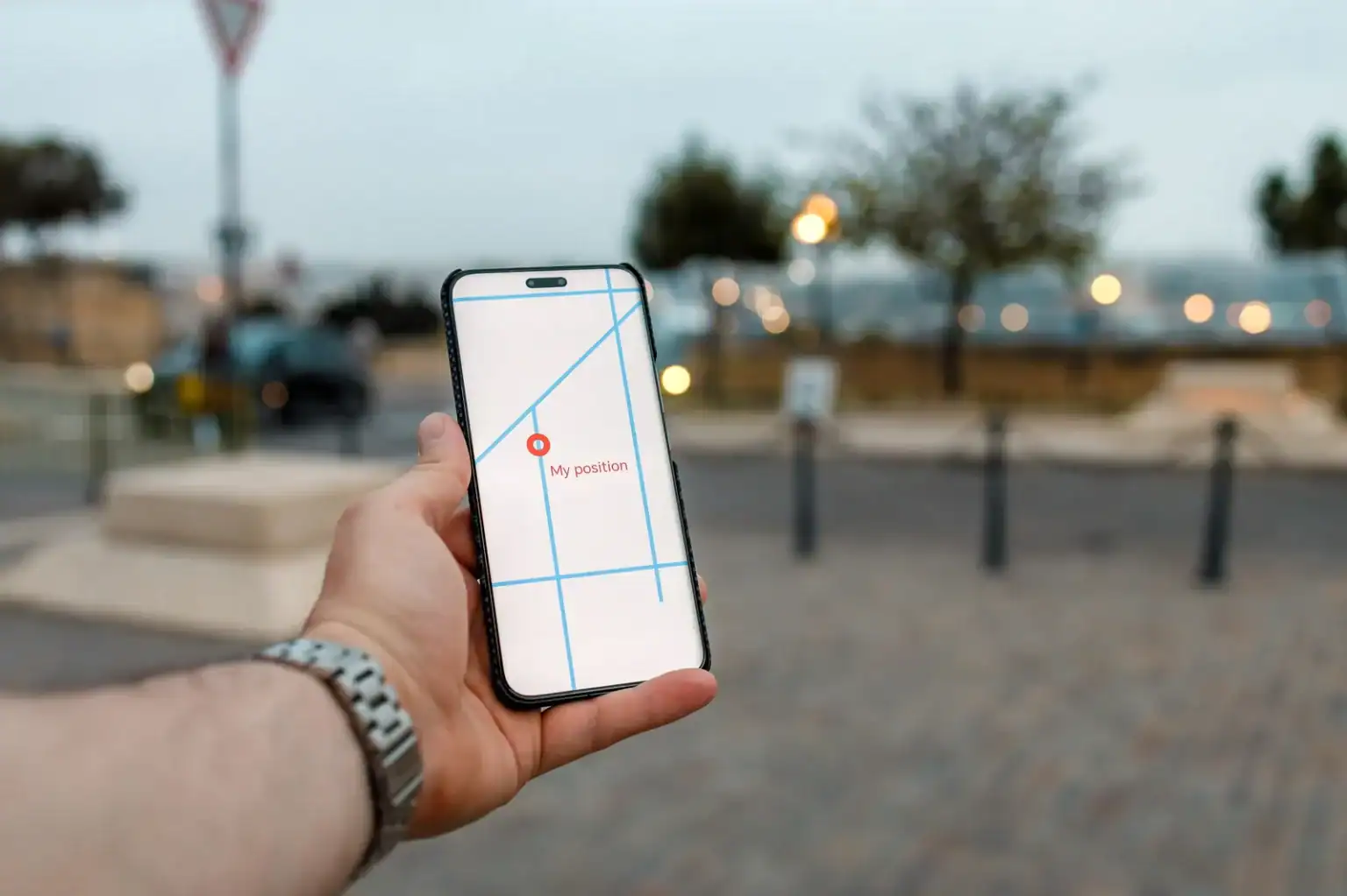 Hand holding a smartphone showing a map and location pin in a town square